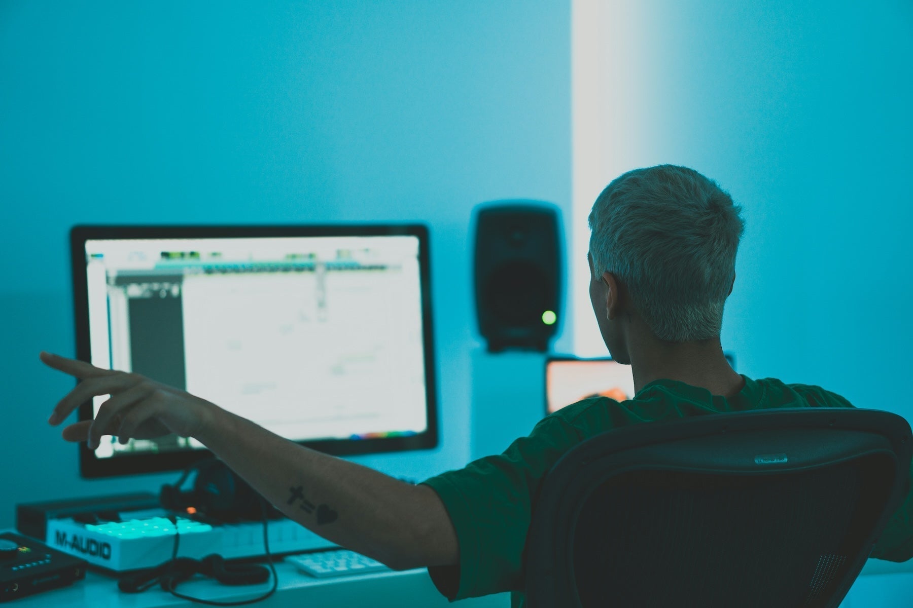 Producer working on a bass patch at a DAW with studio monitors set up for low-end sound design