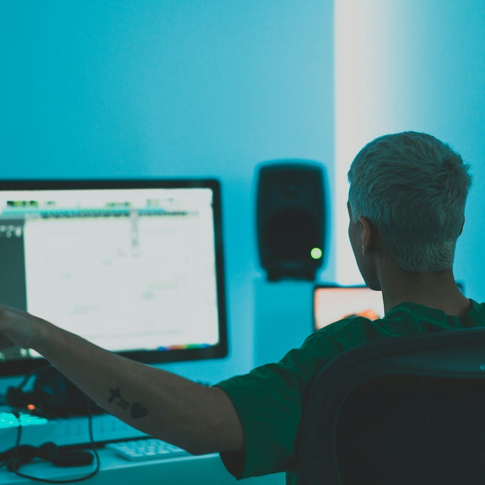 Producer working on a bass patch at a DAW with studio monitors set up for low-end sound design