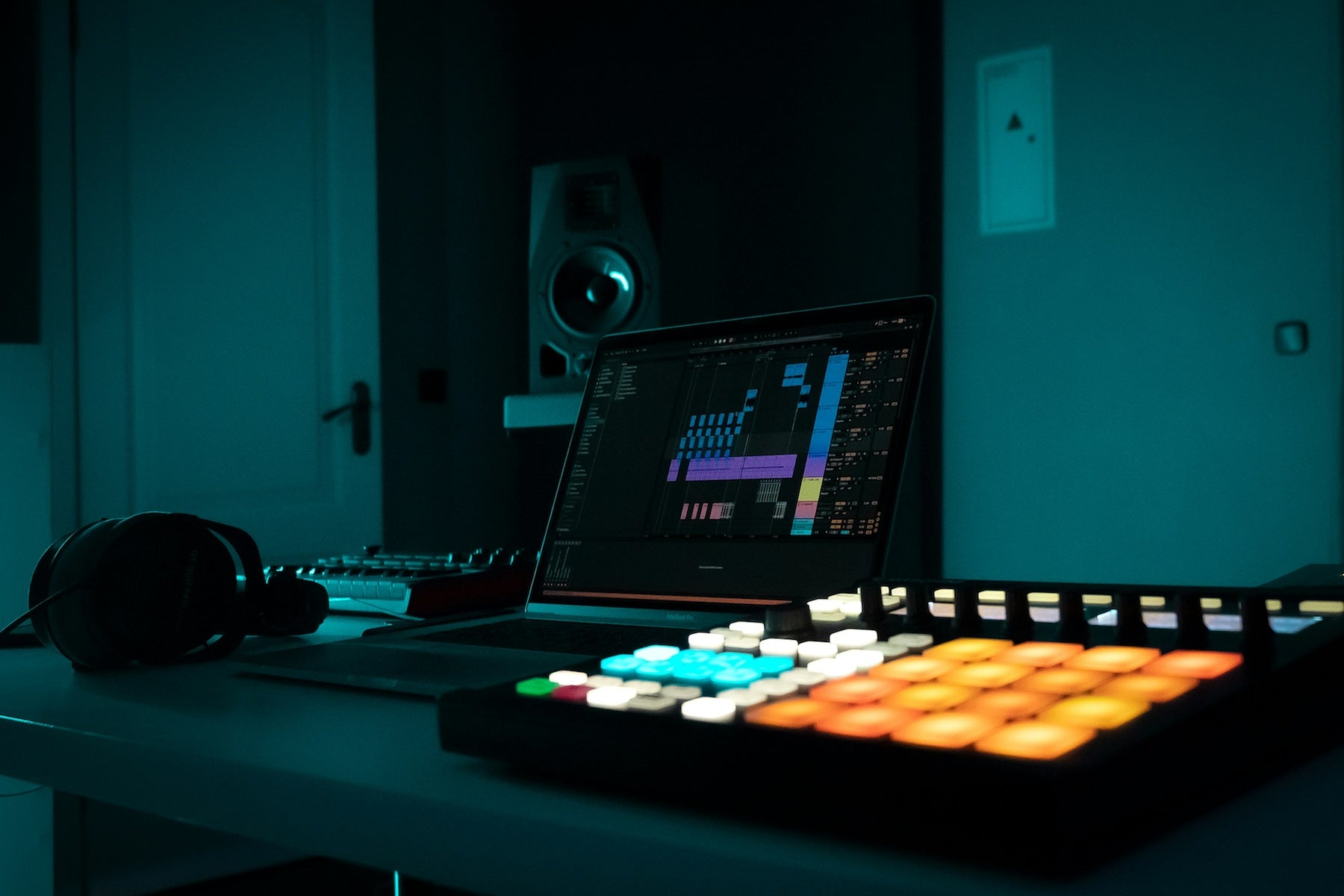 A producer programming drum patterns on a MIDI controller and DAW grid