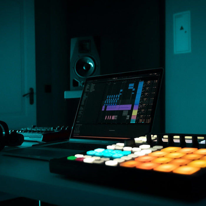 A producer programming drum patterns on a MIDI controller and DAW grid