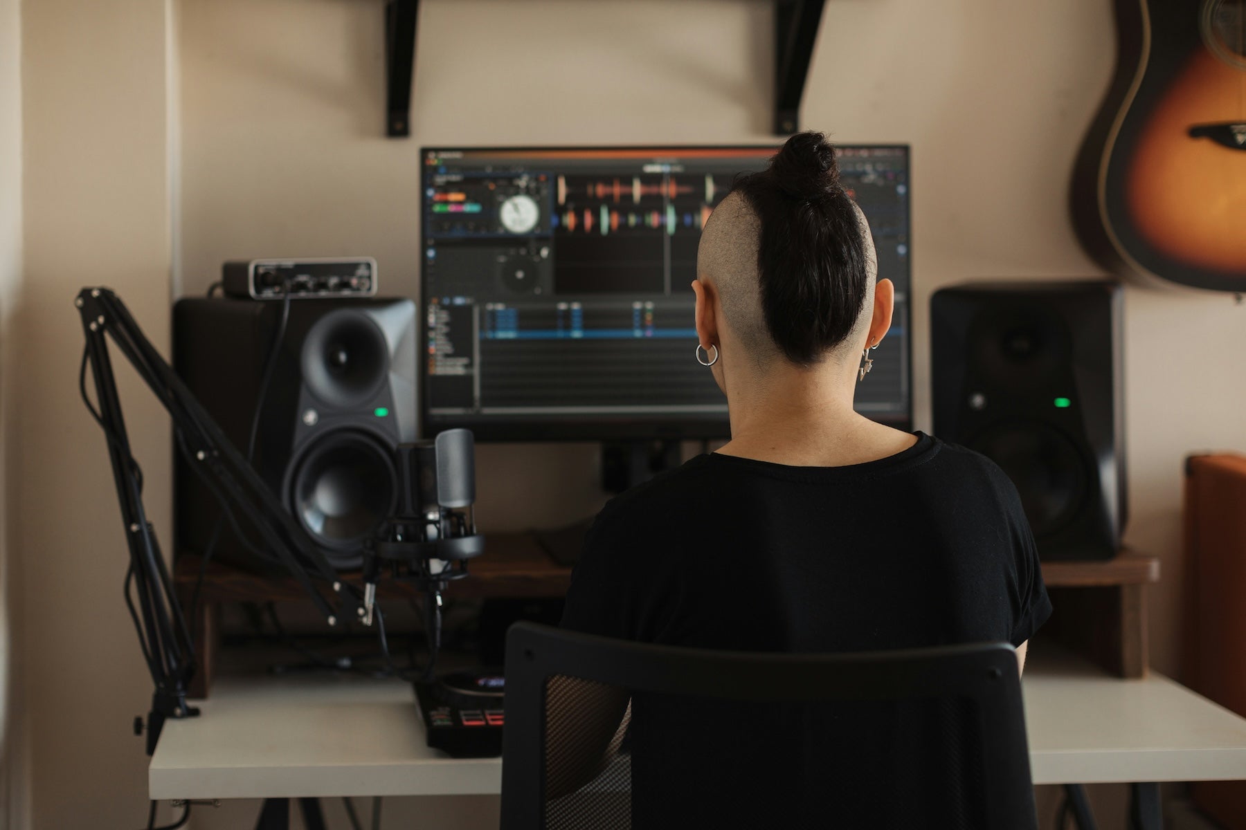 A producer working through a drum and bass mix at their studio workstation