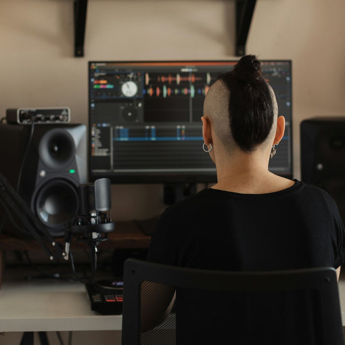 A producer working through a drum and bass mix at their studio workstation