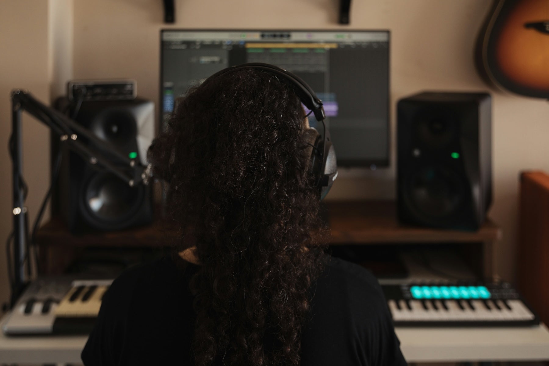 Producer studying a frequency analyser and EQ curve on a studio monitor in a darkened mixing room