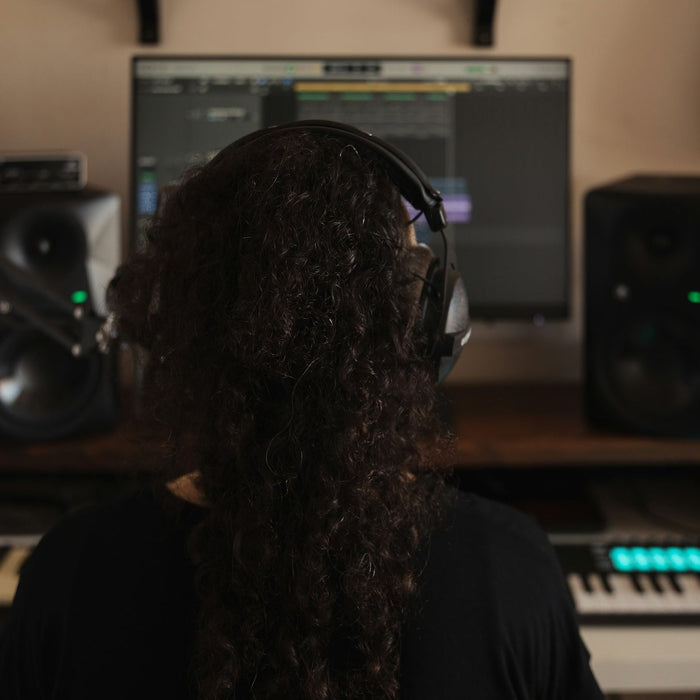 Producer studying a frequency analyser and EQ curve on a studio monitor in a darkened mixing room