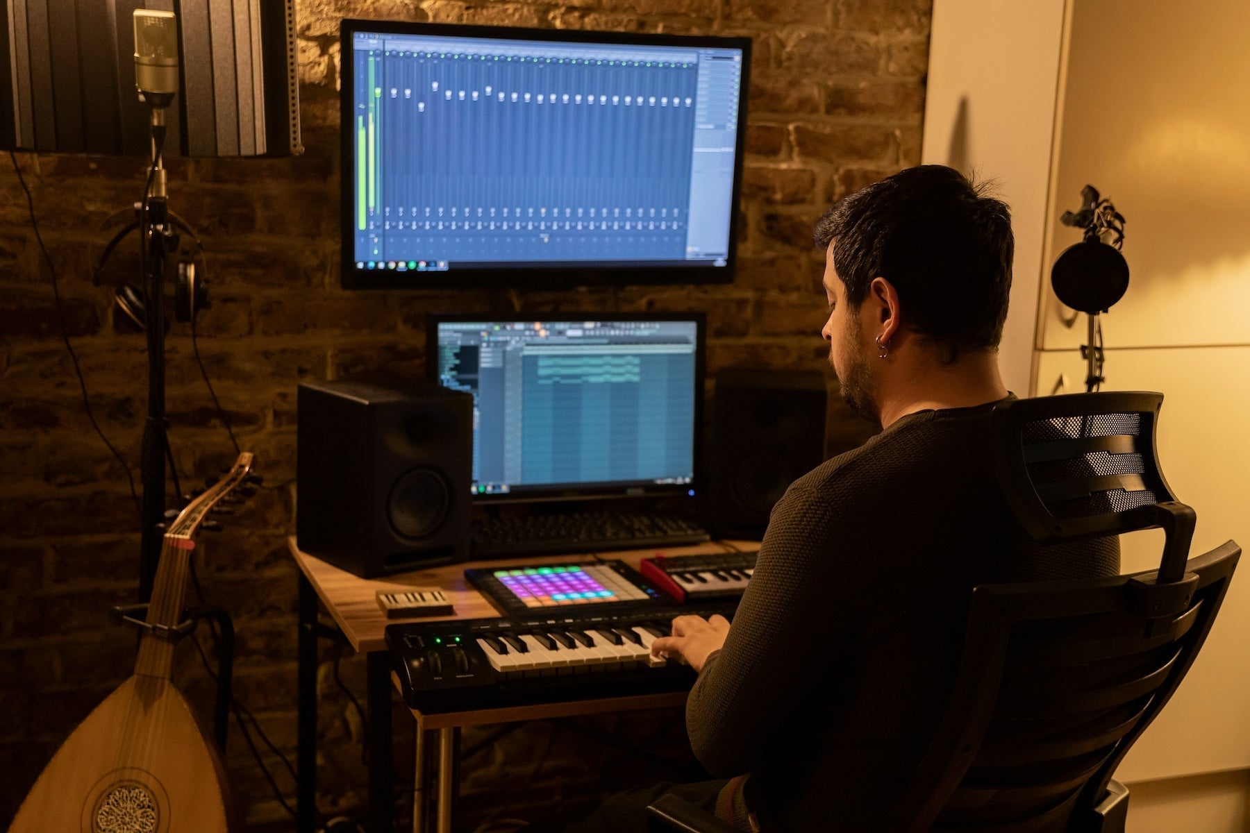 Subwoofer and main monitors set up in a producer's mixing room with bass-heavy waveforms on screen