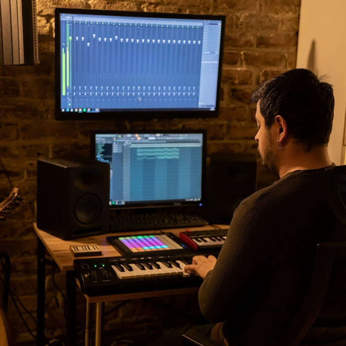 Subwoofer and main monitors set up in a producer's mixing room with bass-heavy waveforms on screen