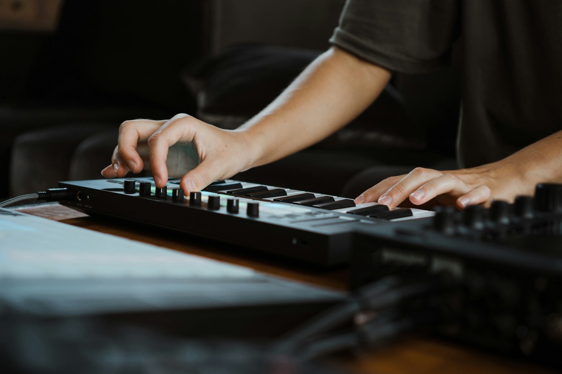 Producer sketching ideas at a MIDI keyboard with a DAW open on screen