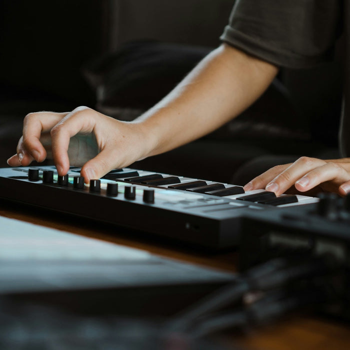 Producer sketching ideas at a MIDI keyboard with a DAW open on screen