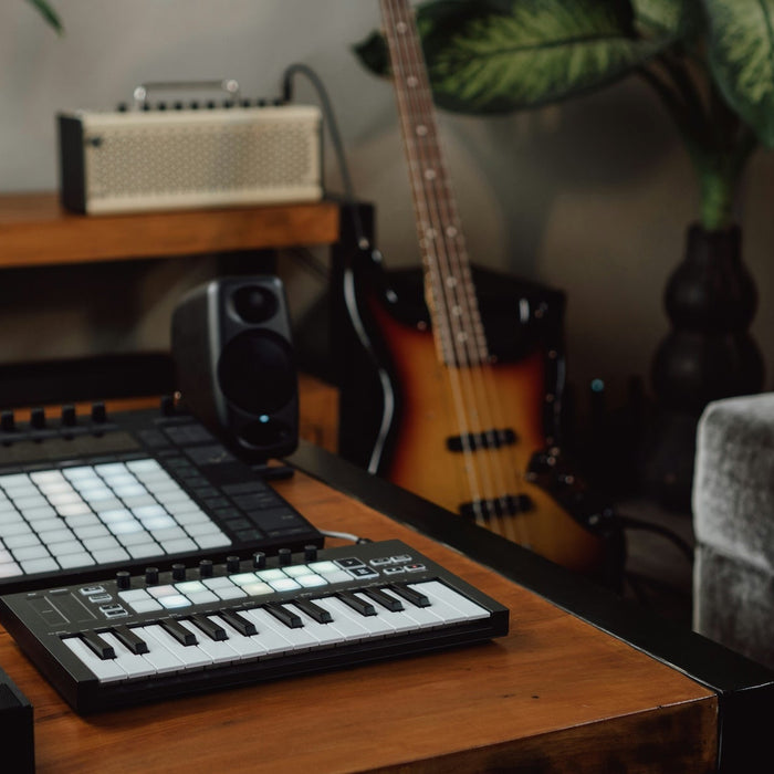 Producer clicking notes into a DAW piano roll on a desktop monitor