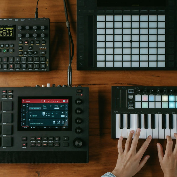 Producer auditioning melodic ideas on a small MIDI keyboard next to a laptop