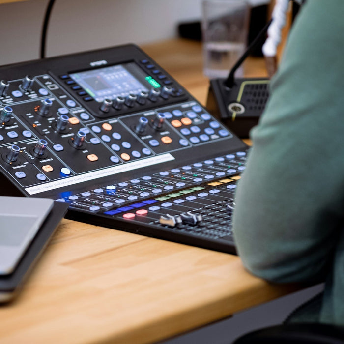 Producer working out chord voicings at a weighted MIDI controller next to studio monitors